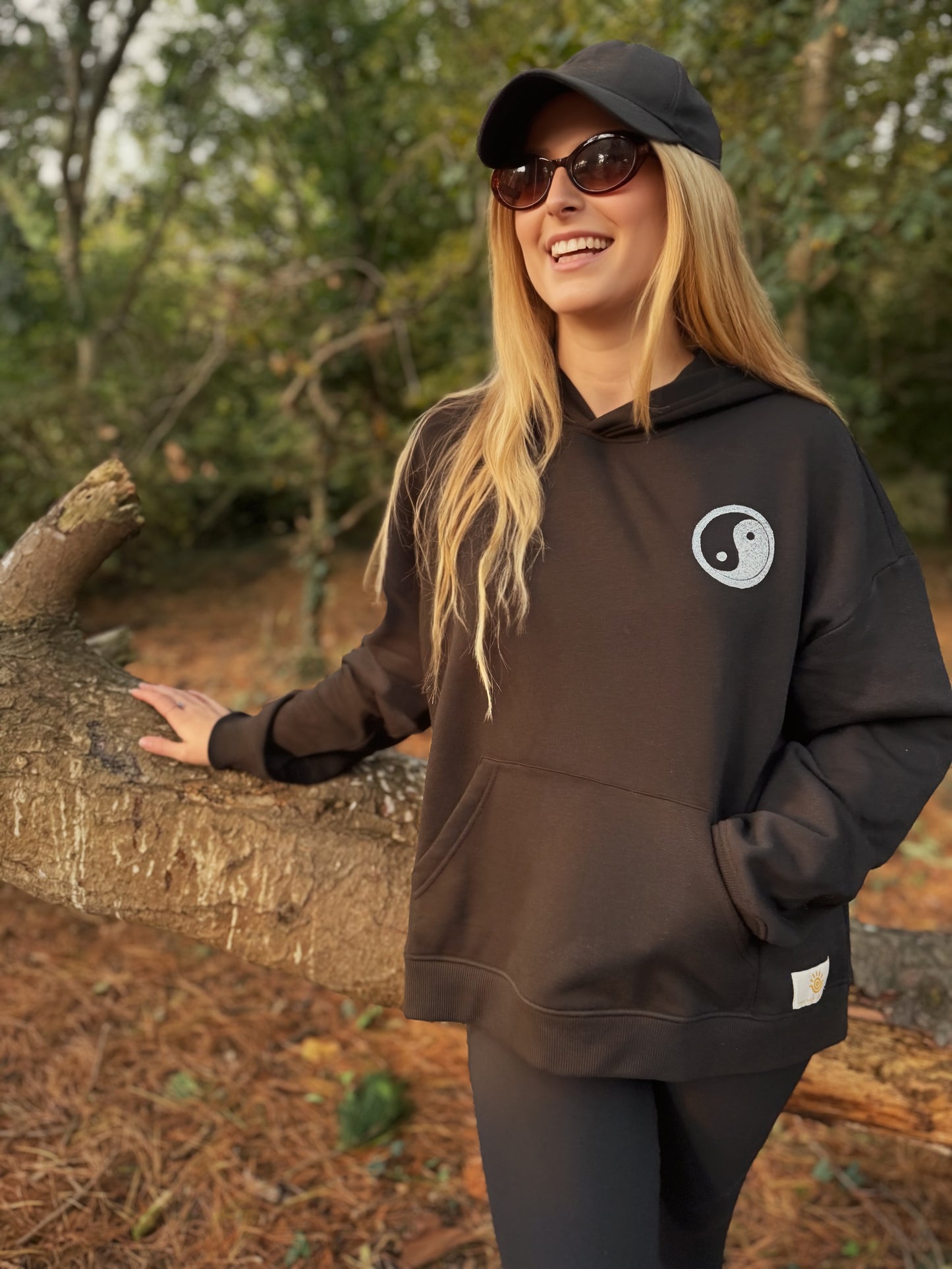 Person wearing a black hoodie with a yin yang symbol outdoors