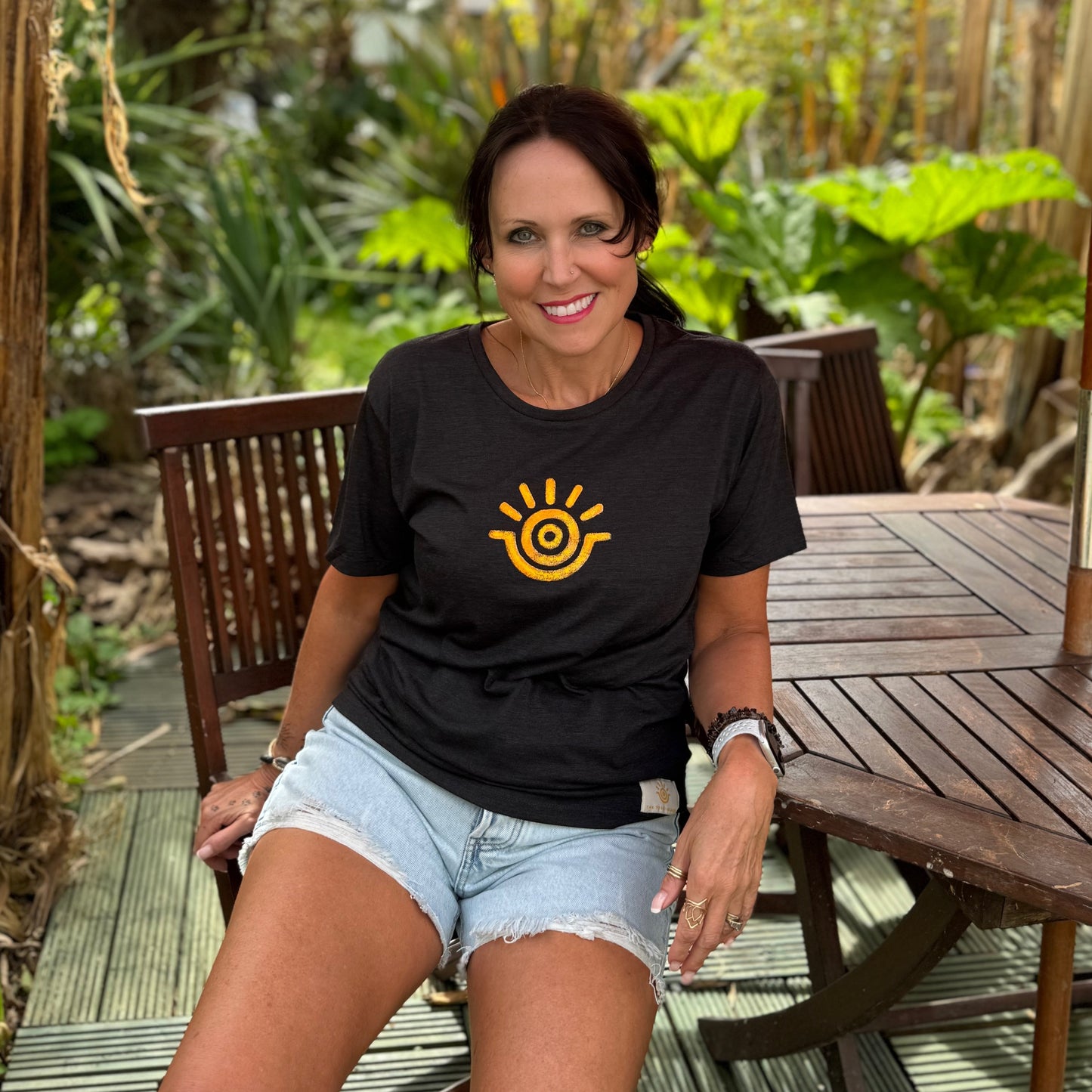 Model wearing positive slogan tee in black with yellow sunshine emblem