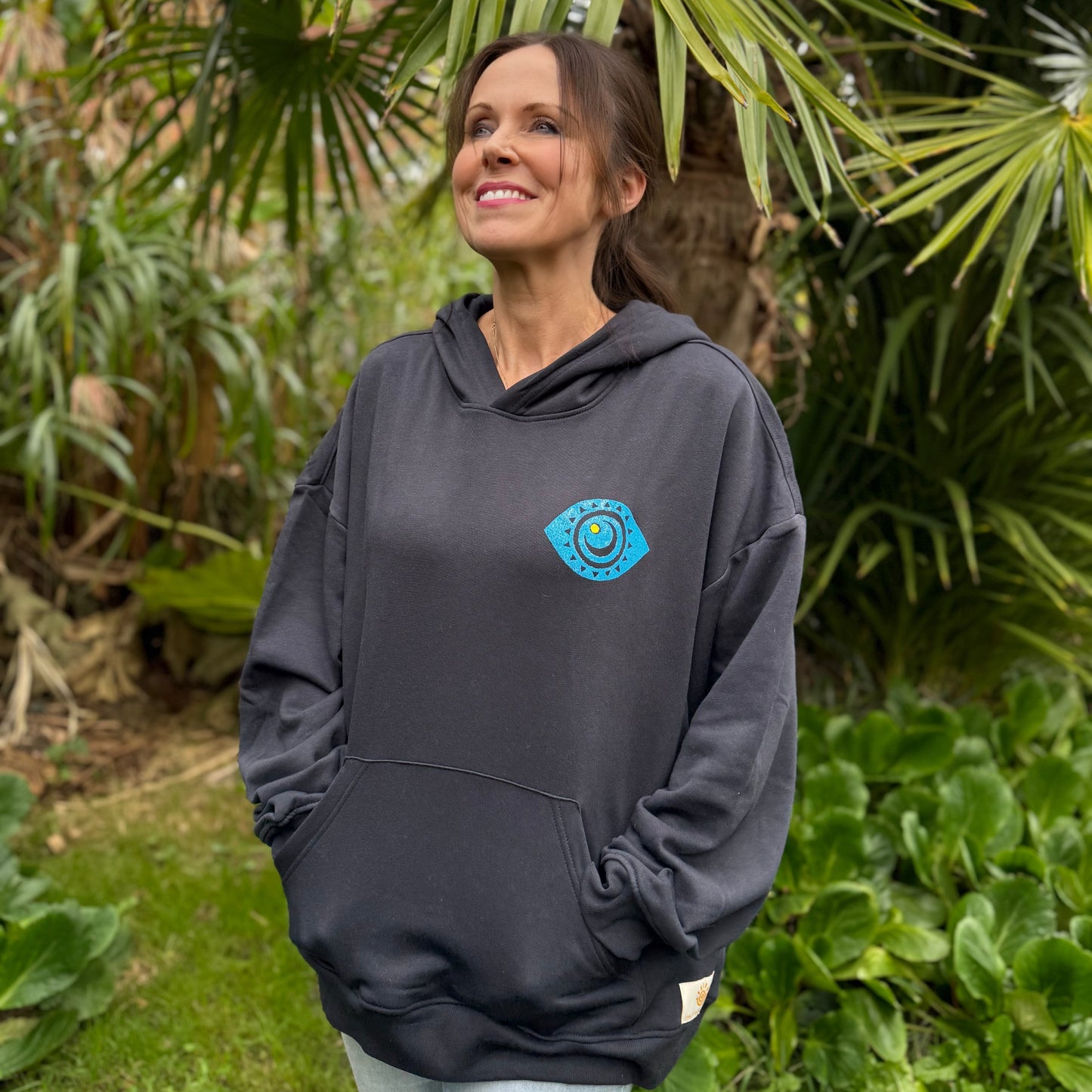 Woman wearing a navy hoodie with a blue logo in a garden setting