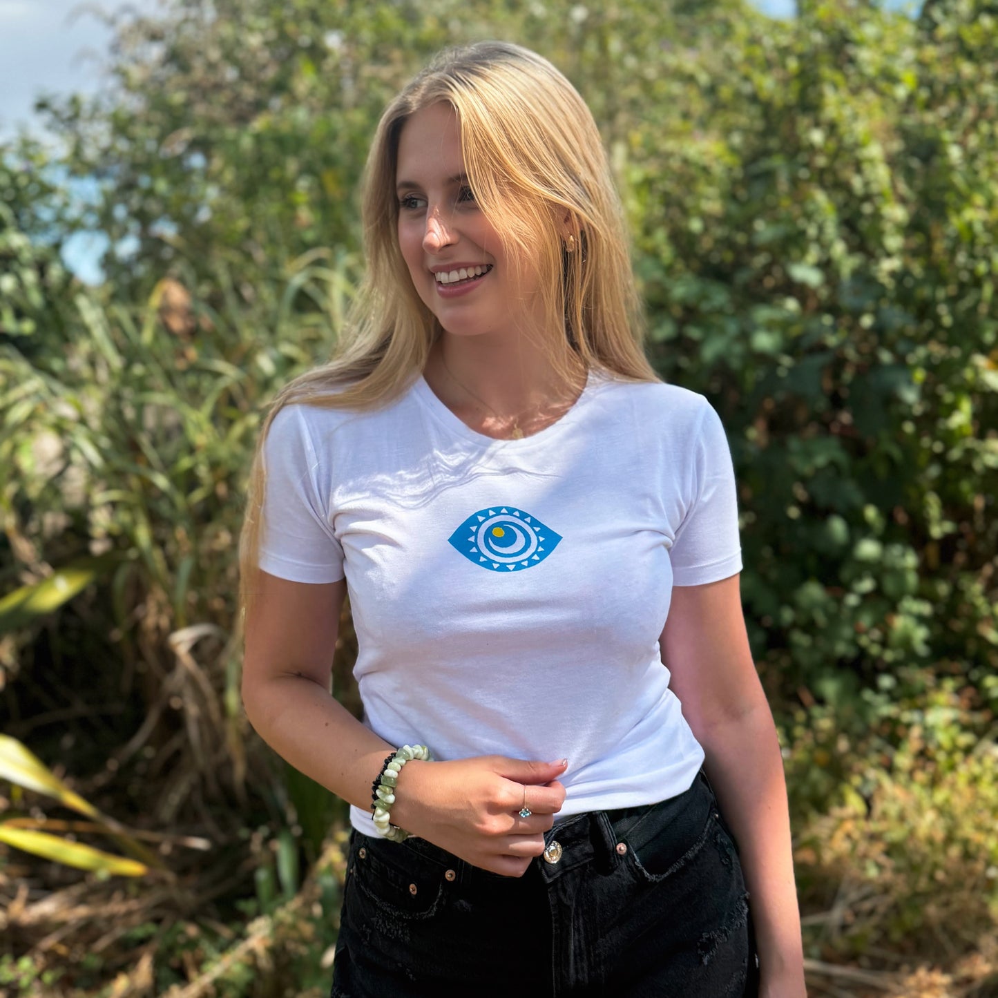 Woman wearing a white t-shirt with a blue eye design outdoors