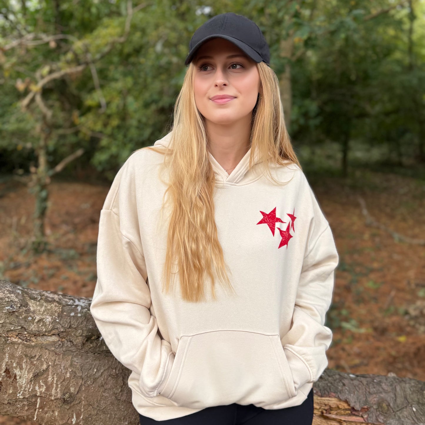 Model wearing cream hoodie with red stars