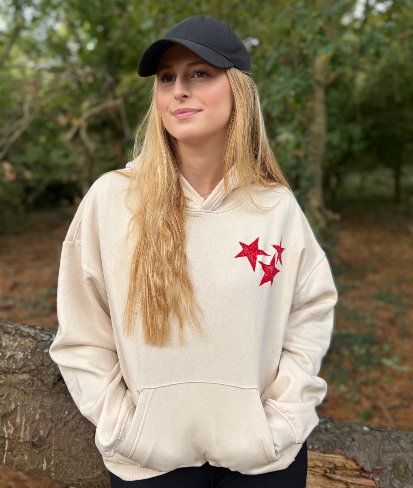 Person wearing a beige hoodie with red star design outdoors