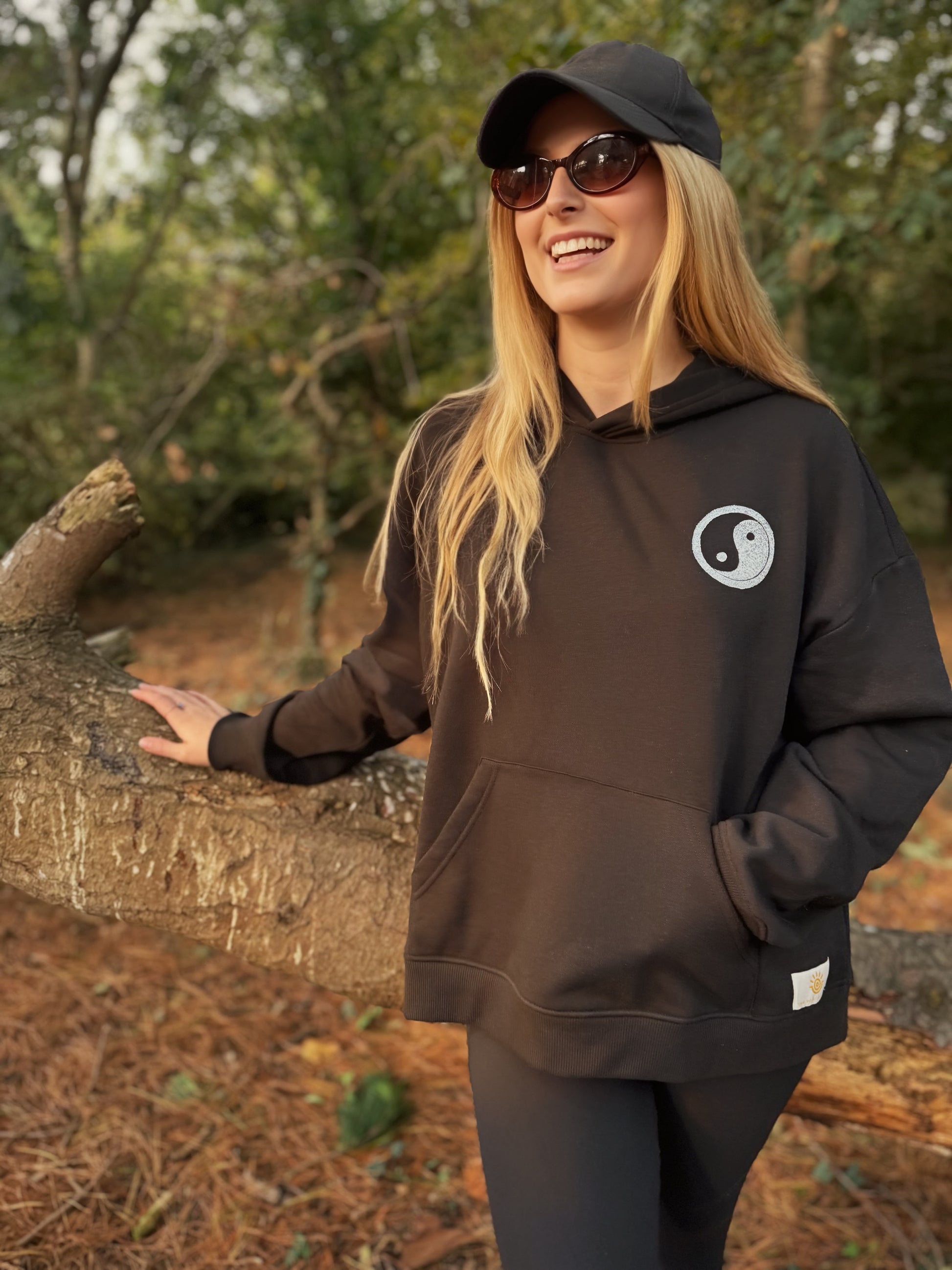 Person wearing a black hoodie with a yin yang symbol outdoors