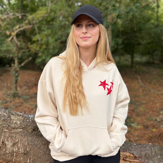 Model wearing cream hoodie with red stars